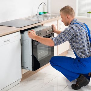 Young Worker Installing Oven In Kitchen