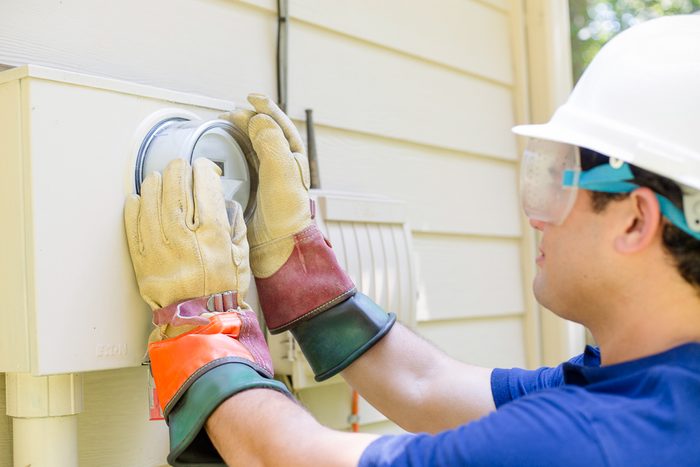 man in safety gear working on outside meter of home