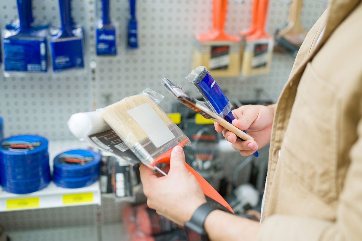customer deciding what paintbrush to buy at hardware store