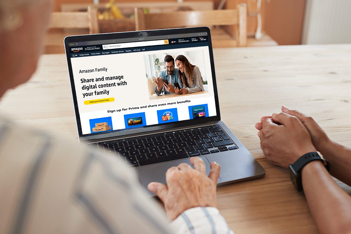 Two persons sitting infront of a laptop with amazon.com page opened in it
