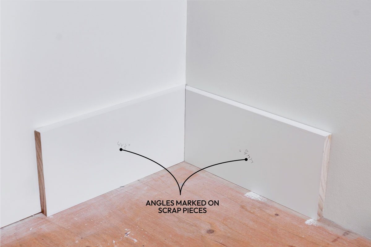 High angle shot of Two white baseboards meet neatly at a corner on a polished wooden floor; surrounded by white walls; ready for final installation and finishing touches;
