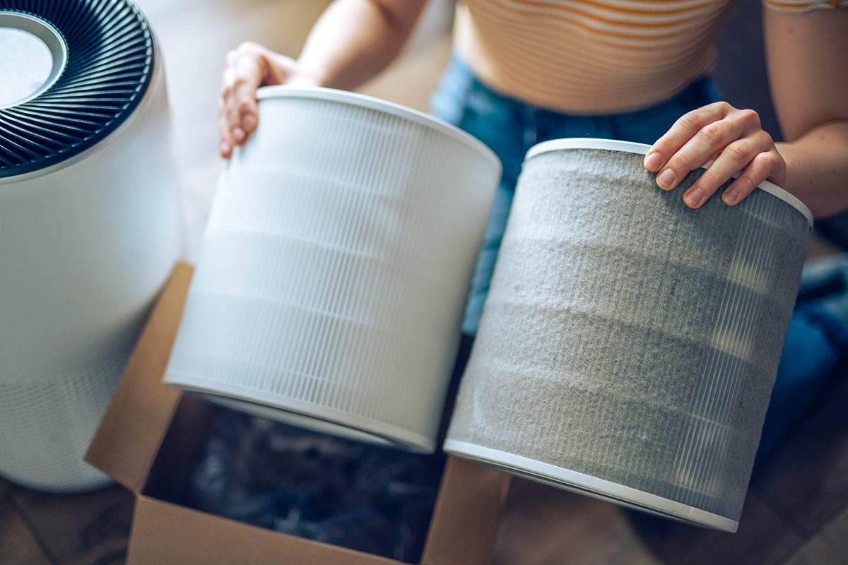 Close up of female hands showing difference between clean and dirty filter on air purifier