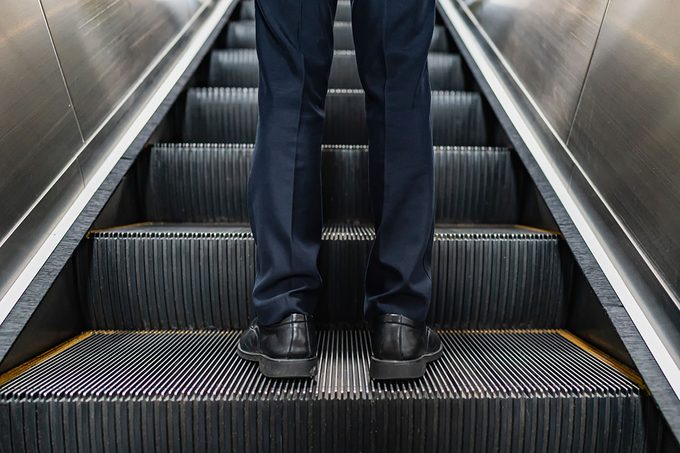 Close-up of feet of business people standing on escalator