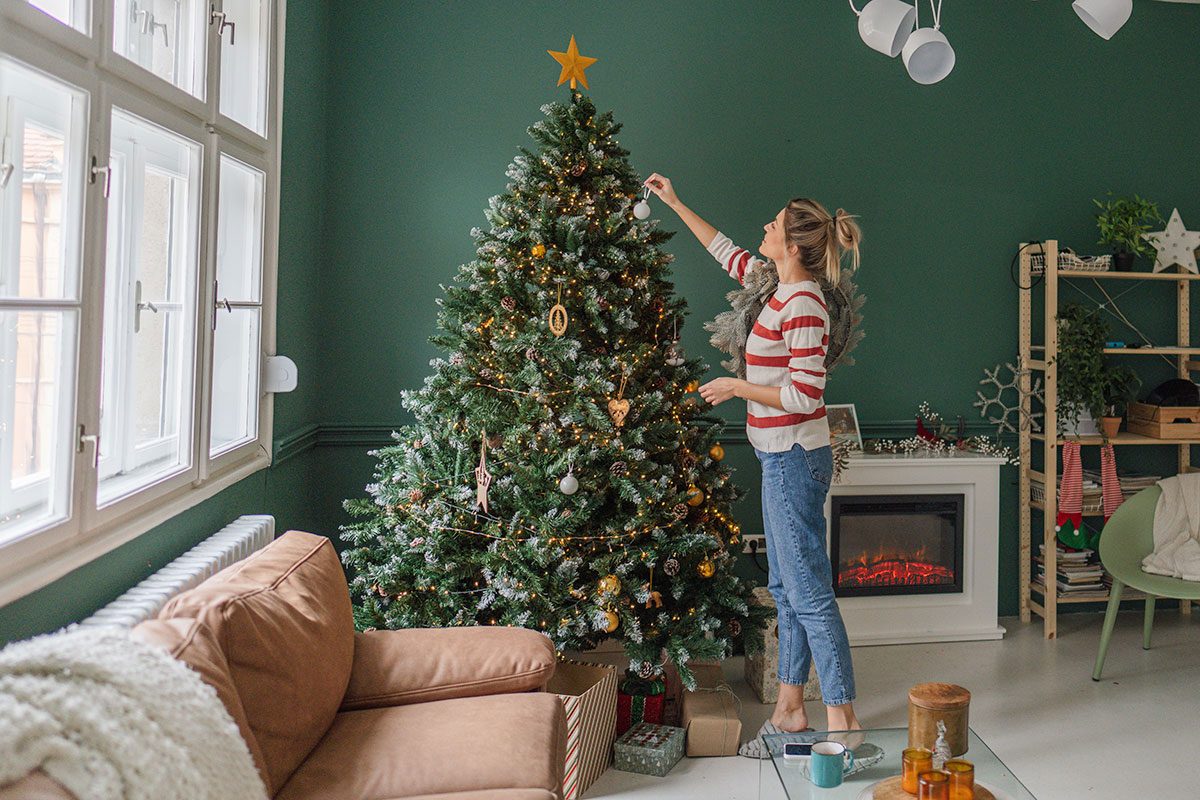 Photo of a young woman decorating Christmas tree at home