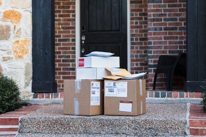 A stack of packages ready for shipping are on the front walkway of the house.
