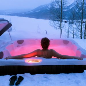 woman relaxing in hot tub in evening in winter