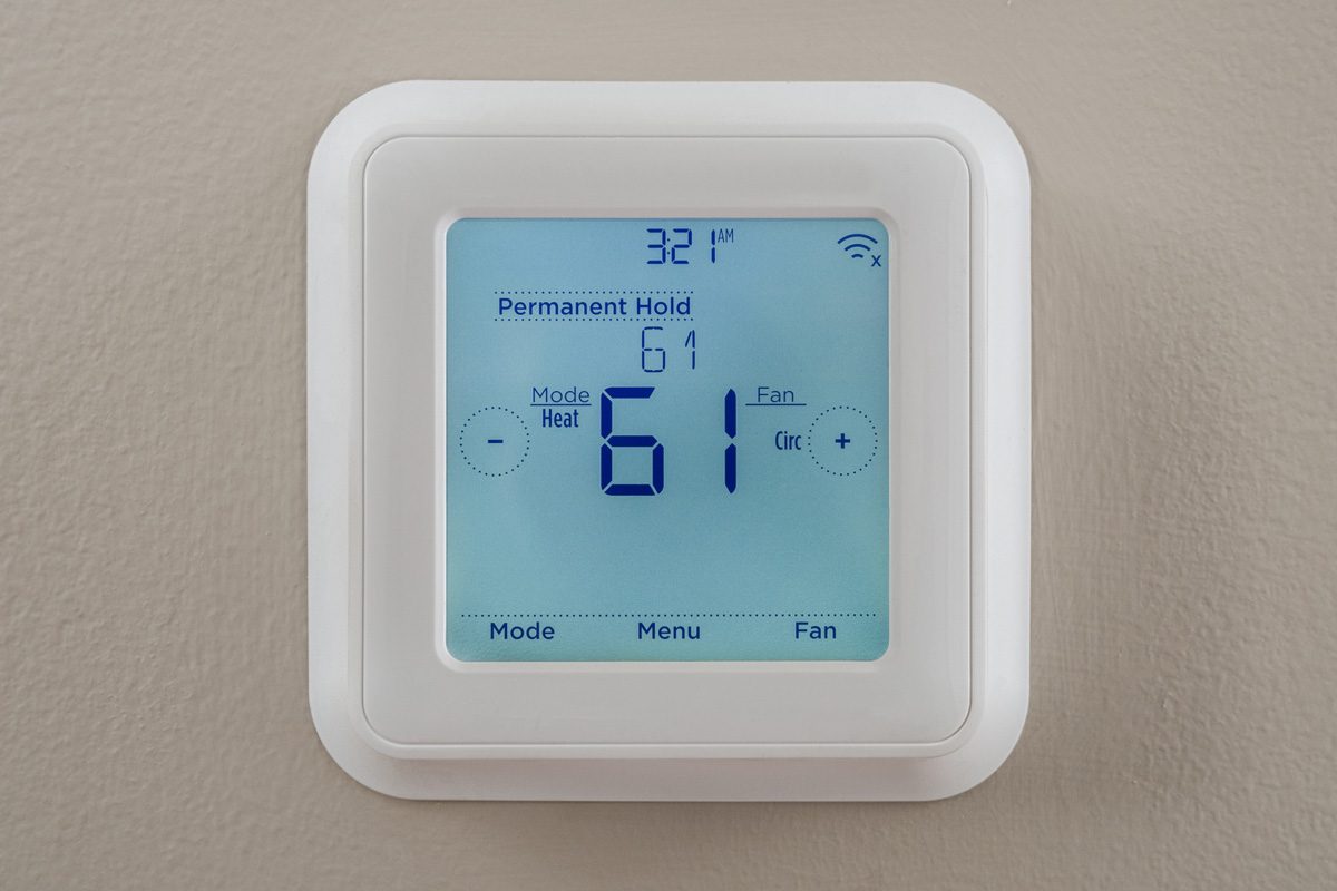 modern residential programmable heating and cooling thermostat mounted on a wall