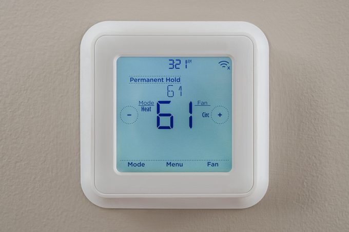 modern residential programmable heating and cooling thermostat mounted on a wall