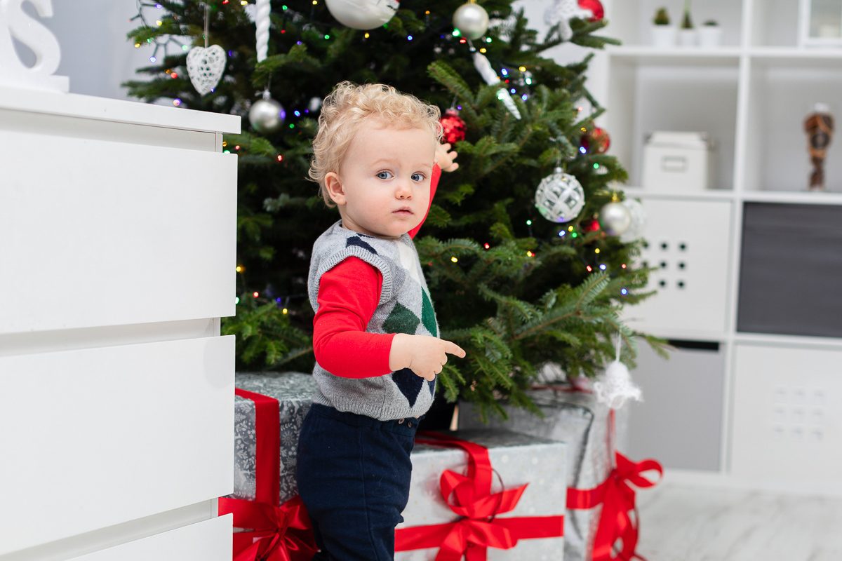 little boy standing by christmas tree