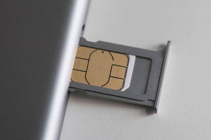 Close-up of sim card and mobile phone on white table