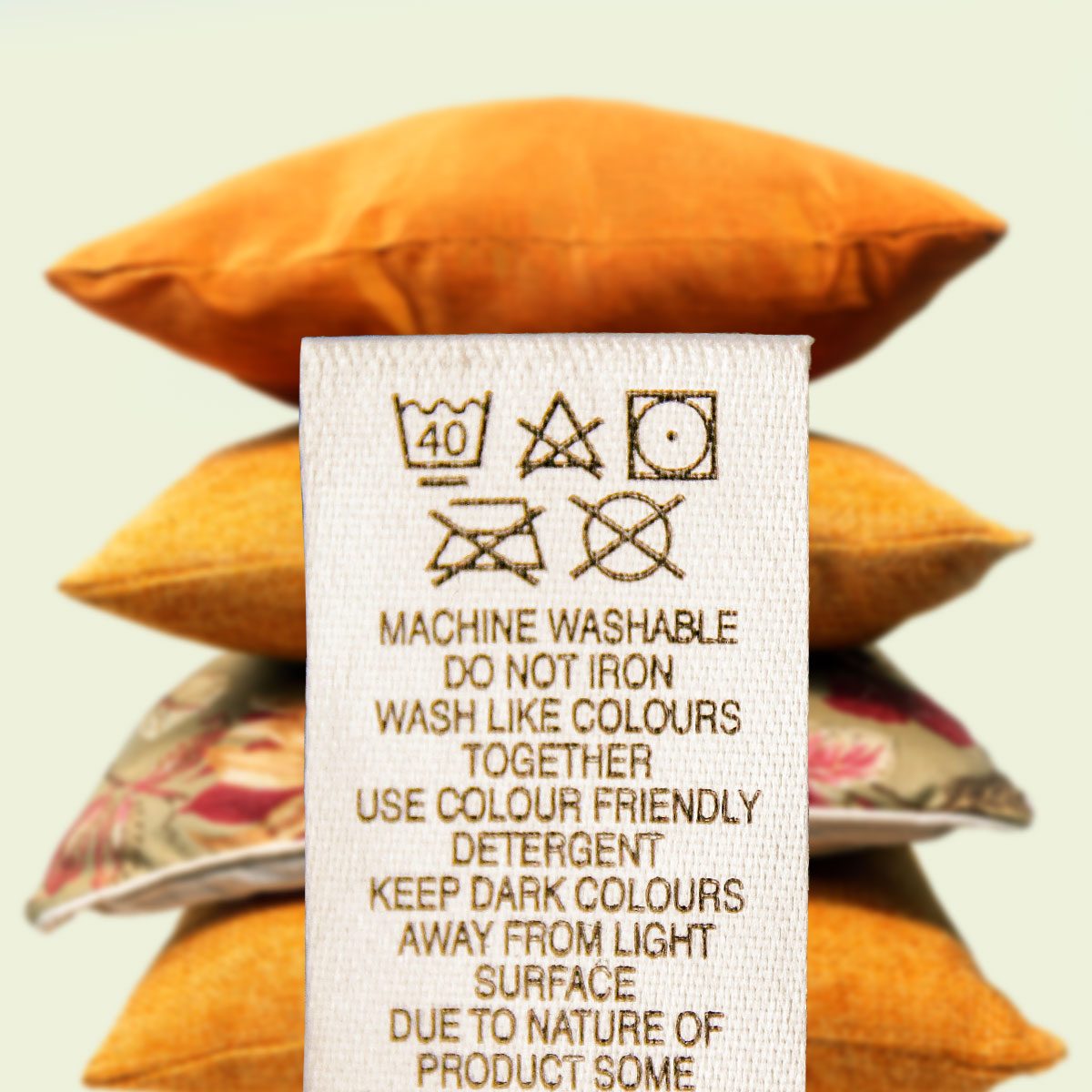 A textile tag in front of stacked yellow pillows