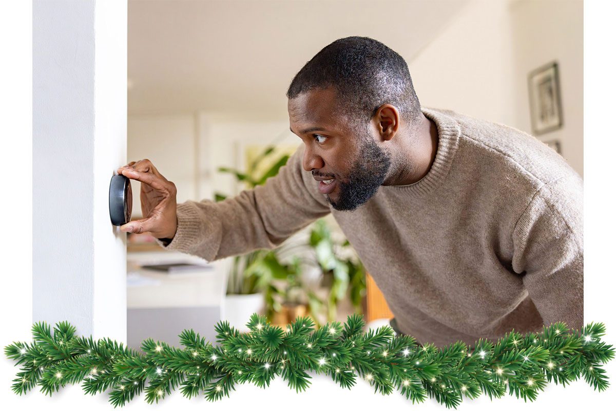 Man at home adjusting the temperature on the thermostat