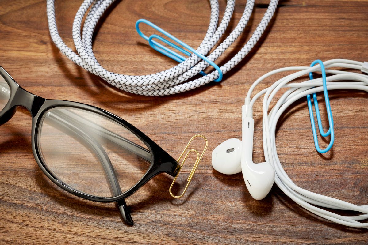 on a wood desk surface, paper clips hold coiled wires together and hold glasses together