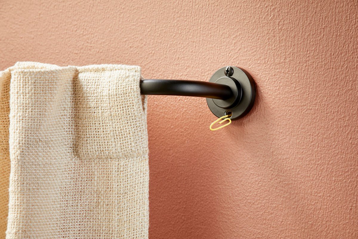paper clip being used to keep curtain rod in place