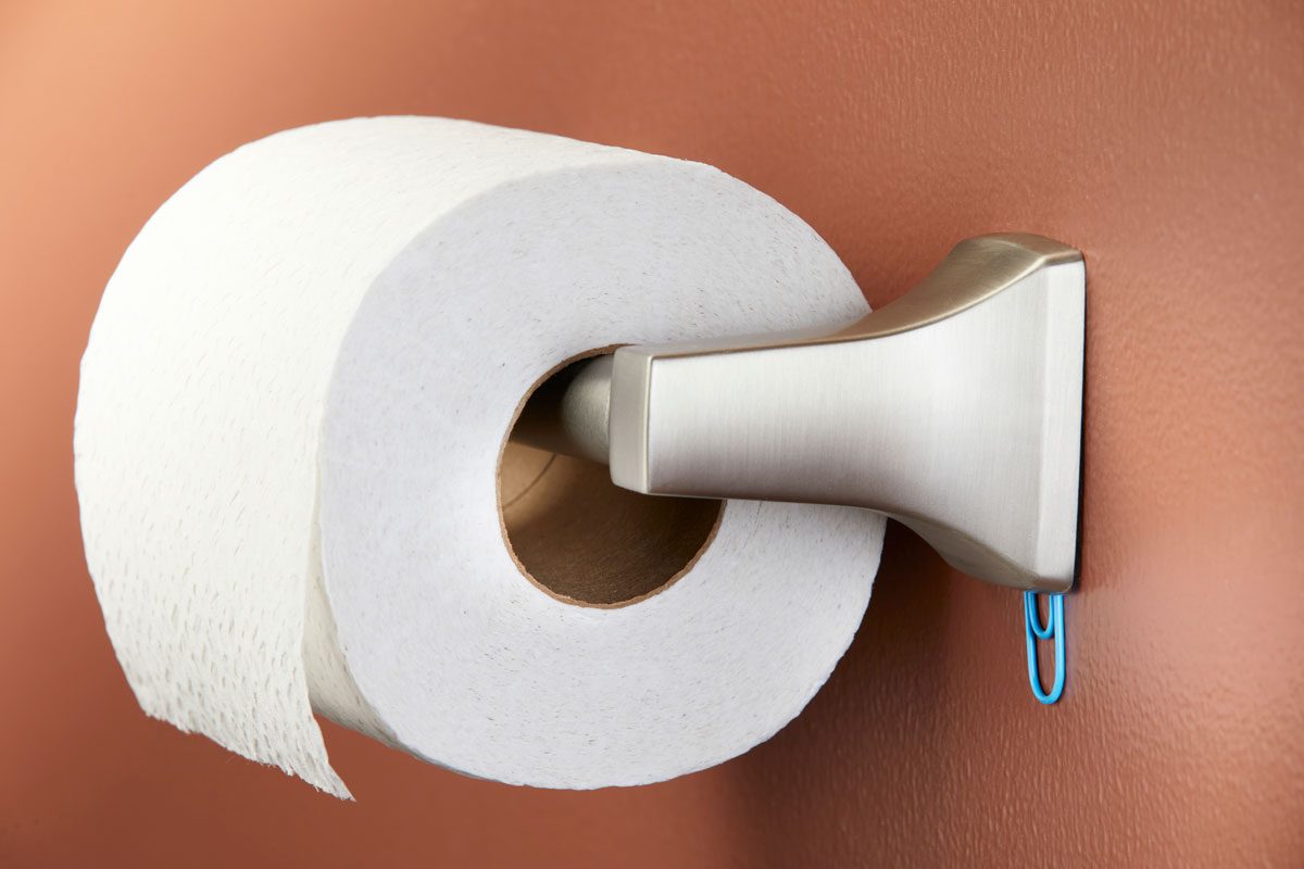 paper clip used as a shim to keep toilet paper roll holder in place