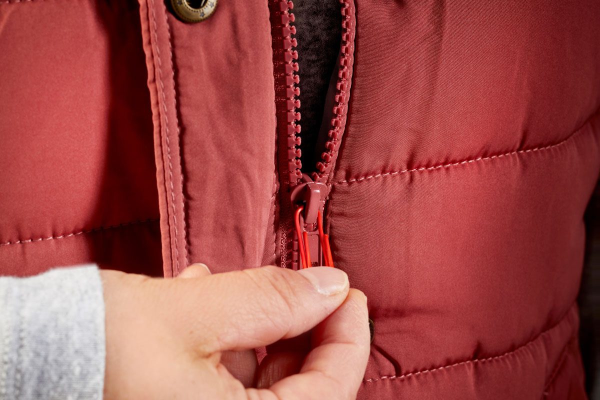 hand using paper clip as a replacement zipper pull on a red vest
